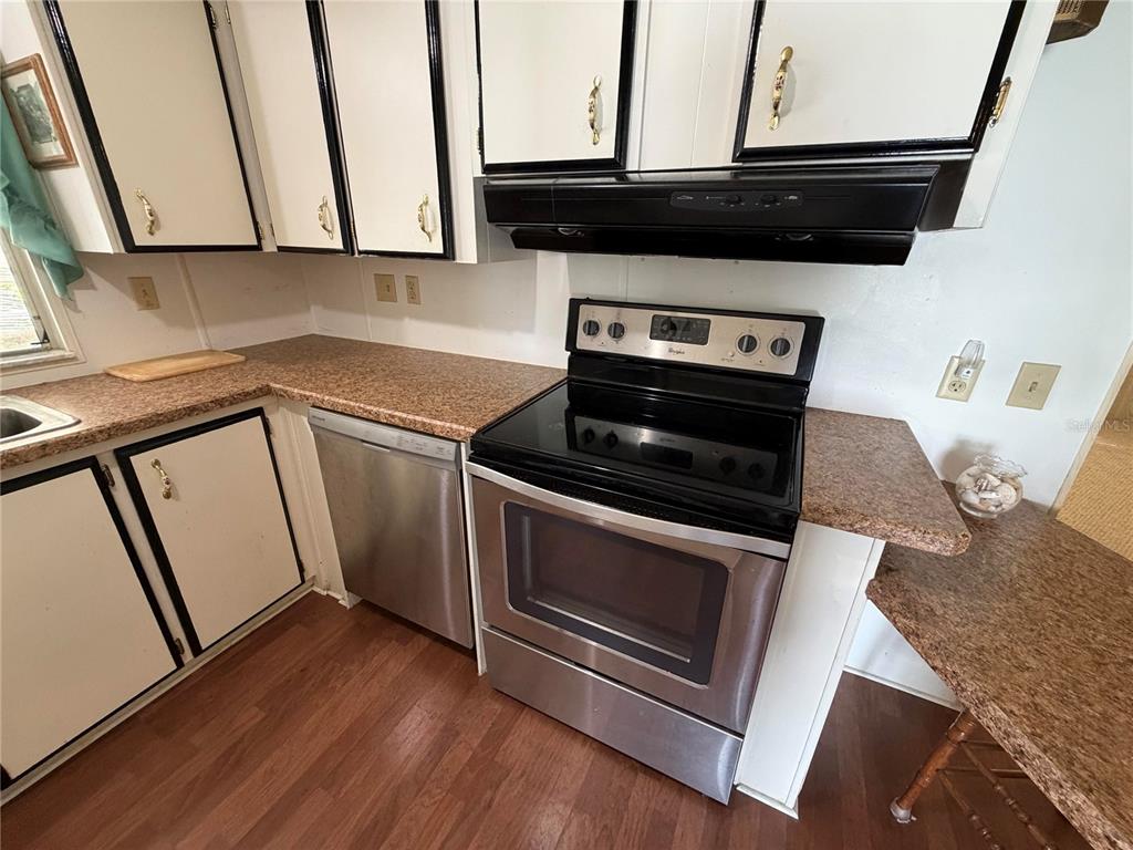 A kitchen features white cabinets with black trim, stainless steel appliances, and speckled laminate countertops — 930 TARRSON BOULEVARD, LADY LAKE, FL