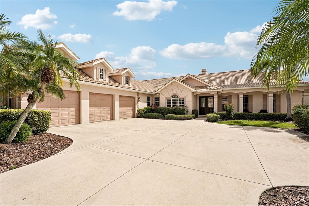 A large, single-story house with a three-car garage and a wide concrete driveway — 6615 BUTLERS CREST DRIVE, BRADENTON, FL