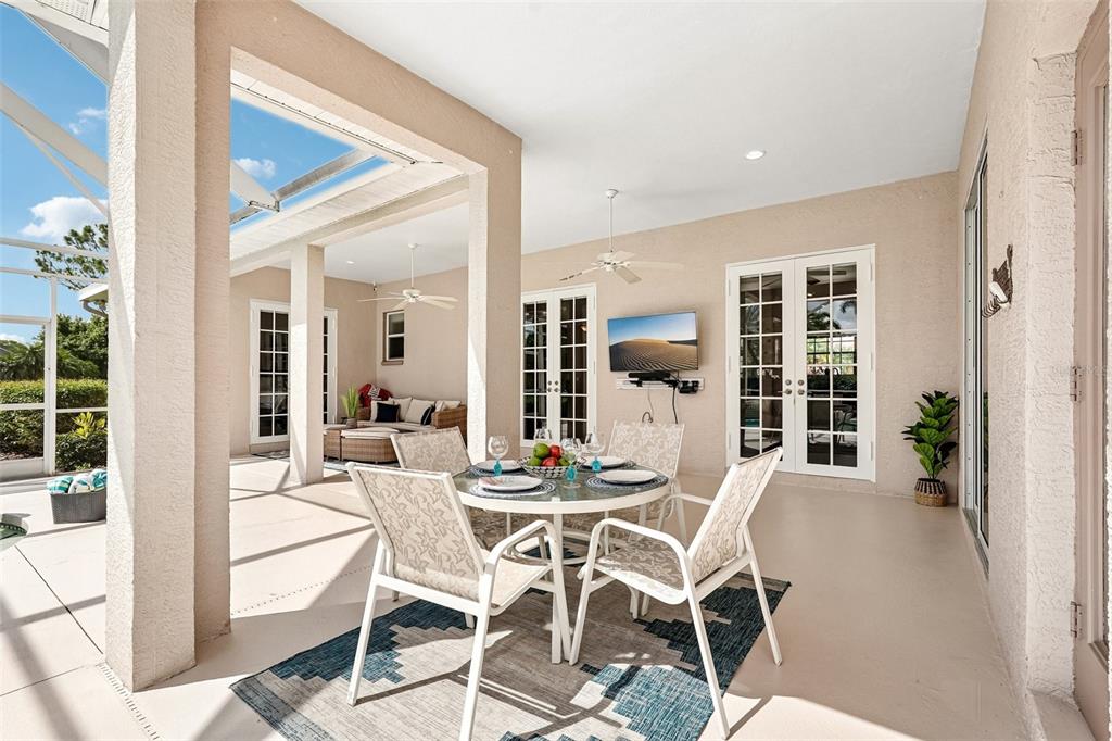 A covered outdoor patio features a dining set, a television, and a seating area — 6615 BUTLERS CREST DRIVE, BRADENTON, FL