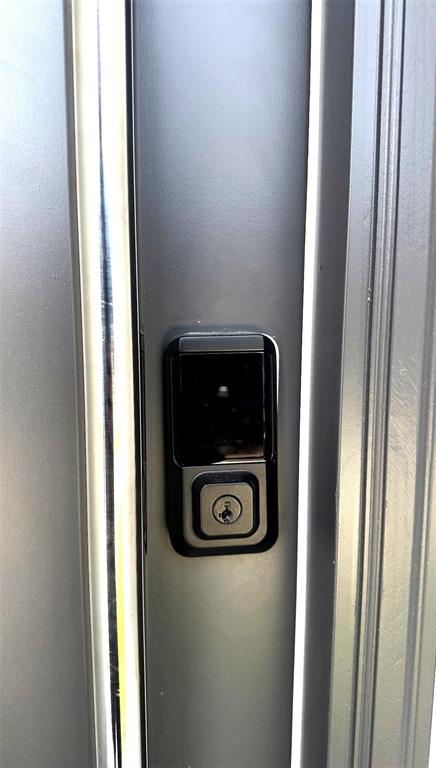 A close-up view of a black smart lock installed on a dark gray door — 8796 POSITIVITY DRIVE, KISSIMMEE, FL