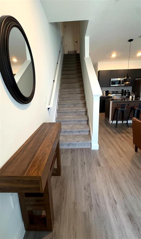 A hallway features a wooden console table, a round mirror, carpeted stairs, and a kitchen — 8796 POSITIVITY DRIVE, KISSIMMEE, FL
