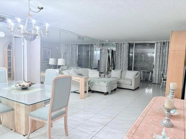 A dining area with a glass table leads into a living room with mirrored walls — 2671 S Course Drive S # 108, Pompano Beach FL 33069, POMPANO BEACH, FL
