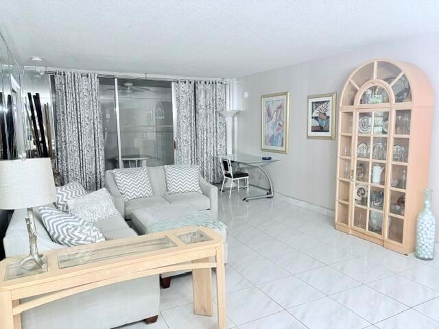 A living room features light-colored tile floors, a sectional sofa, and a large display cabinet — 2671 S Course Drive S # 108, Pompano Beach FL 33069, POMPANO BEACH, FL