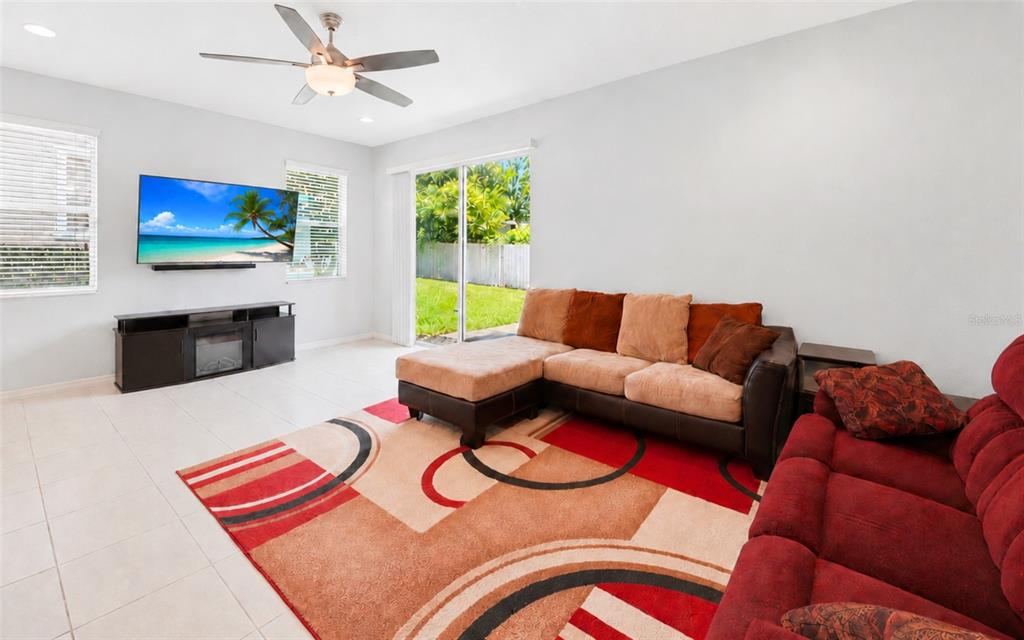 A living room features a large area rug, multiple sofas, and an open kitchen area — 1136 E 10TH STREET, APOPKA, FL
