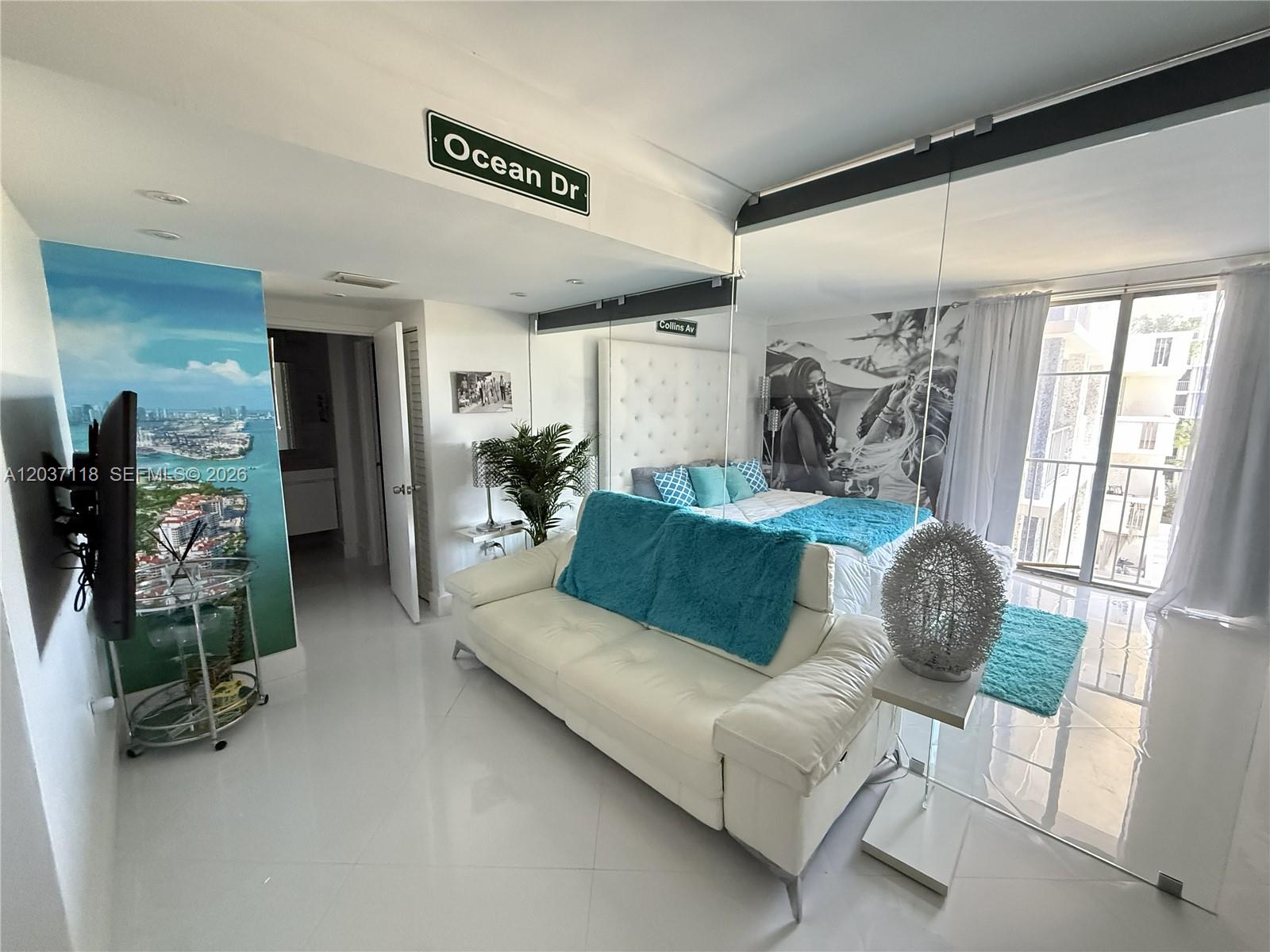 A studio apartment features a white sofa, a bed, and a mirrored wall partition — 800 West Ave # 605, Miami Beach FL 33139, MIAMI BEACH, FL