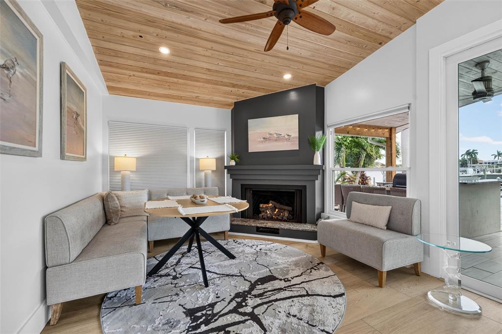 A dining area features a corner banquette, round table, fireplace, and wood-paneled ceiling — 8009 13TH AVENUE S, ST PETERSBURG, FL