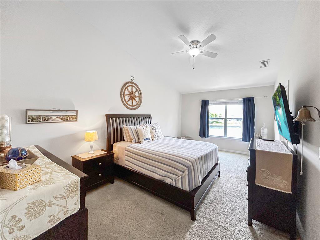 A bedroom features a dark wood bed frame, a ceiling fan, and a window view — 2749 CLUB CORTILE CIRCLE, KISSIMMEE, FL