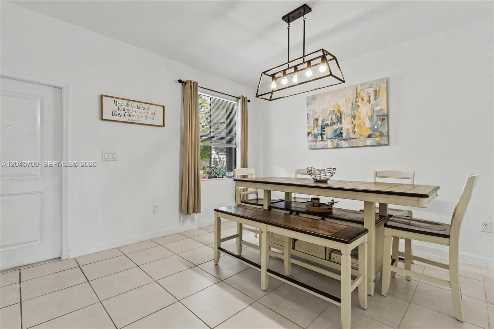 A dining room features a wooden table with benches, a rectangular light fixture, and tile flooring — 18102 SW 148th Rd, Miami FL 33187, MIAMI, FL