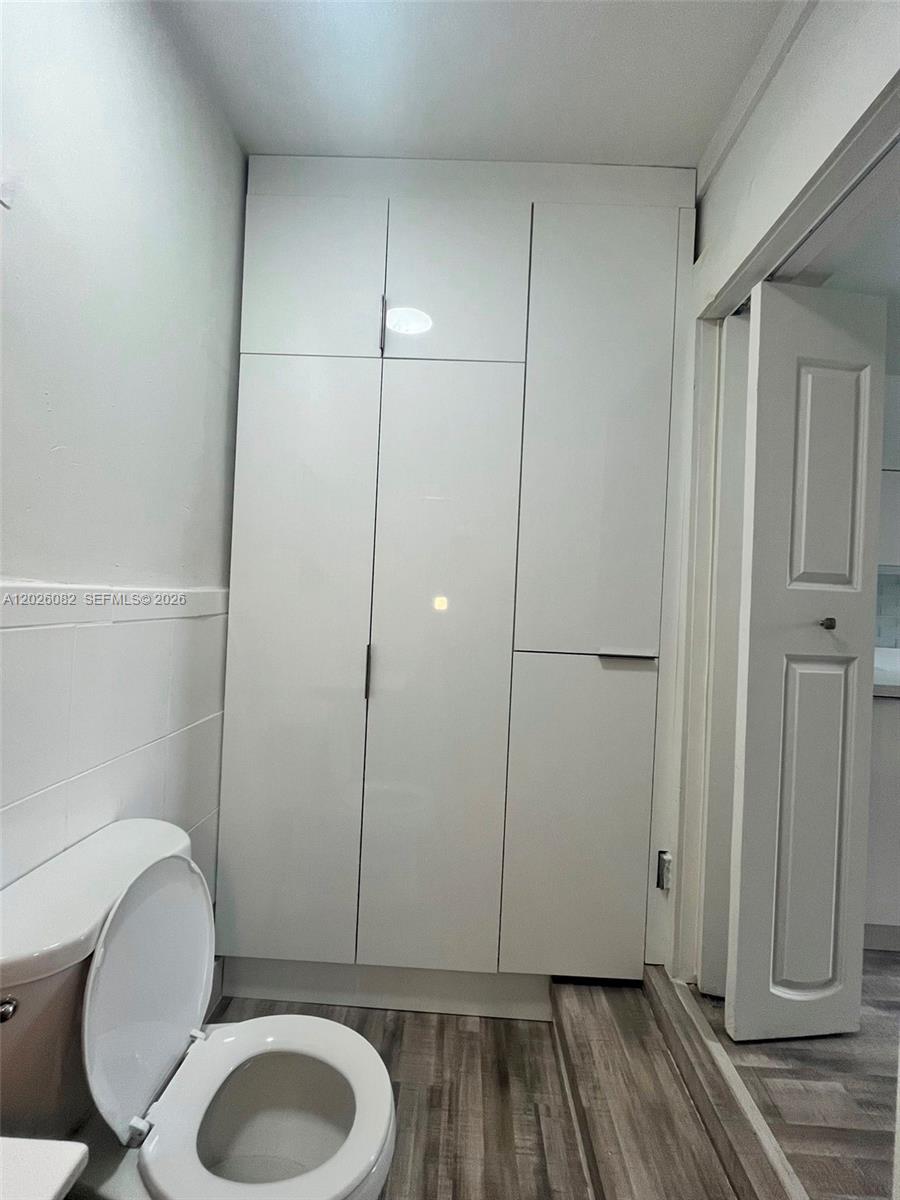 A bathroom features a white toilet and a tall, white, modern storage cabinet — 1845 NW 114th St # 0, Miami FL 33167, MIAMI, FL