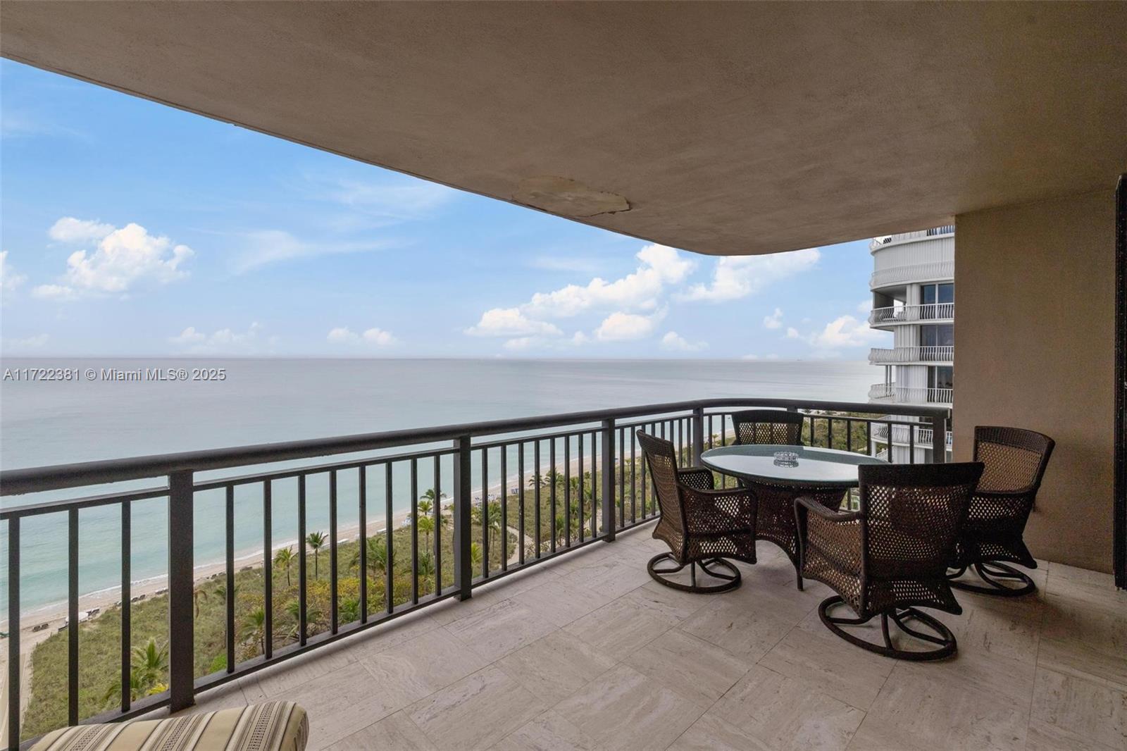 A balcony with a glass-topped table and wicker chairs overlooks the ocean and beach — 10175 Collins Ave # 1202, Bal Harbour FL 33154, BAL HARBOUR, FL