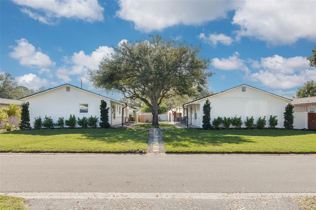 Two white single-story buildings face each other across a grassy yard with a large tree — 544 93RD AVENUE N, ST PETERSBURG, FL