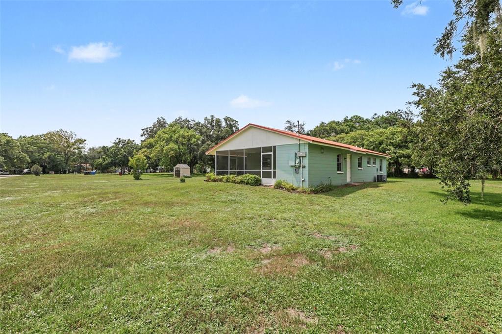 A light green house with a screened-in porch sits on a large, grassy lot — 3149 SYDNEY DOVER ROAD, DOVER, FL