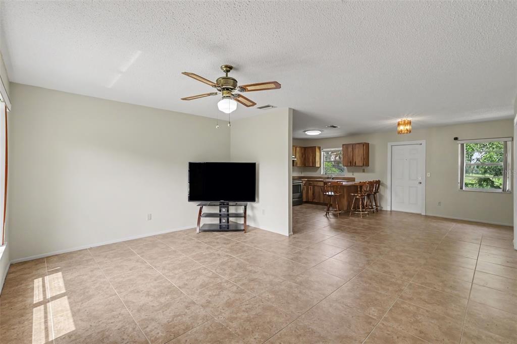 A living room with tile flooring opens into a kitchen with wooden cabinets and bar seating — 3149 SYDNEY DOVER ROAD, DOVER, FL