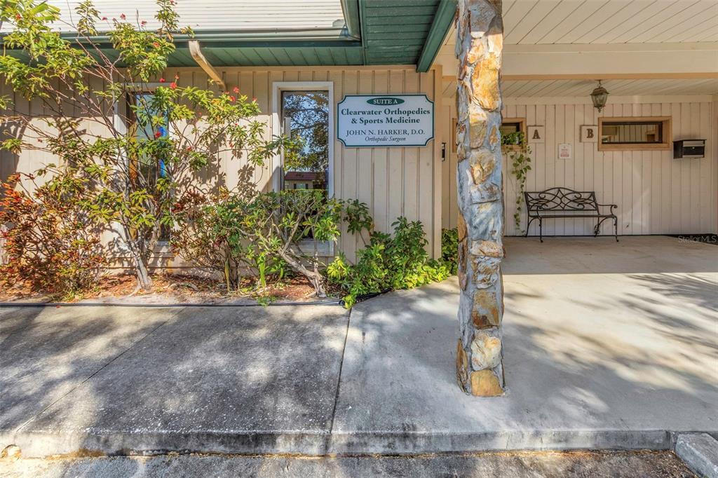 The exterior of a medical office building features a stone pillar and a bench — 701 N HERCULES AVENUE, CLEARWATER, FL