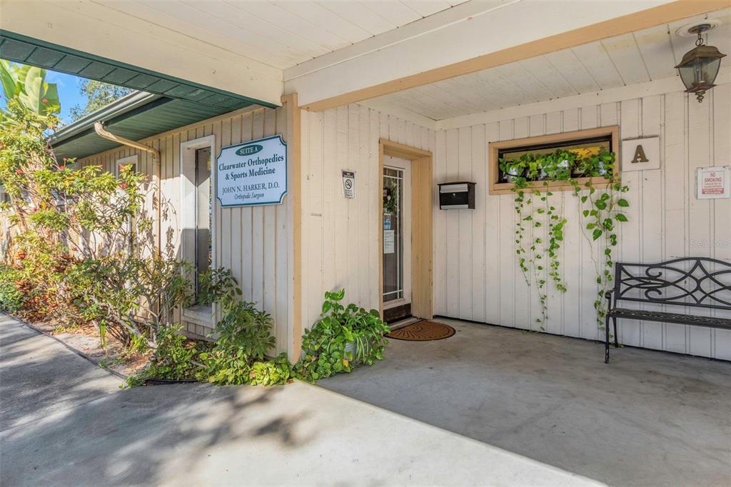 The exterior entrance of a medical office suite features a sign, bench, and potted plants — 701 N HERCULES AVENUE, CLEARWATER, FL