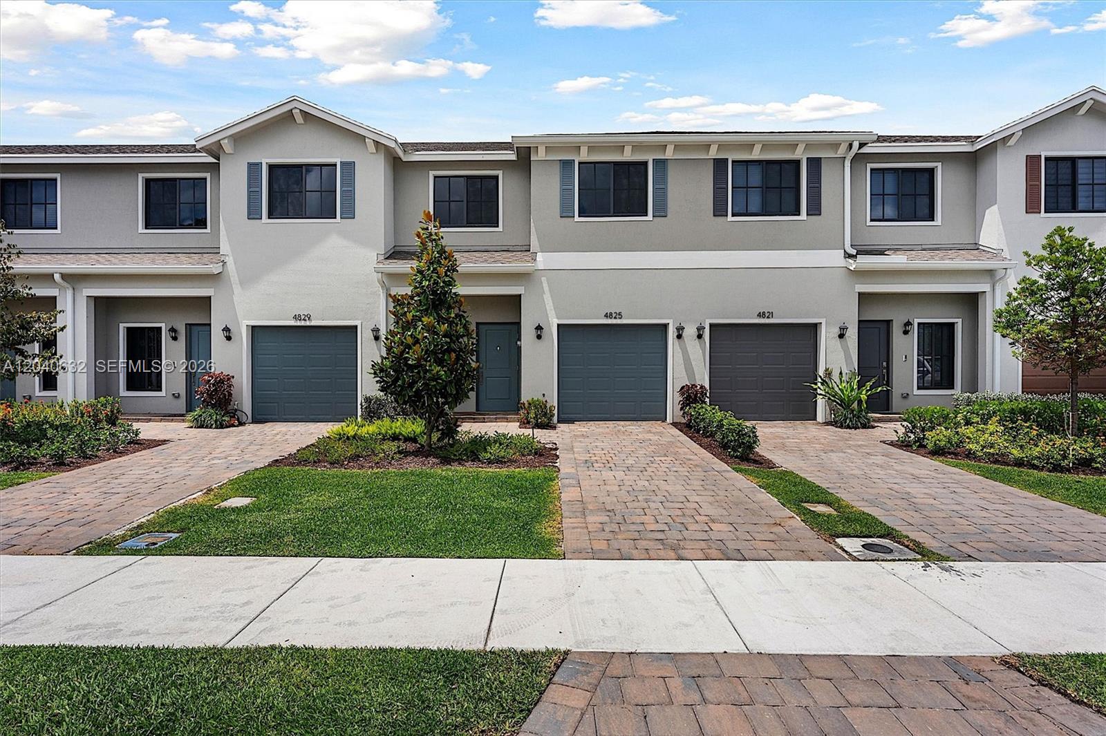 A row of three two-story townhouses features gray garage doors and paved driveways — 4825 Dillion St, Lake Worth FL 33463, LAKE WORTH, FL