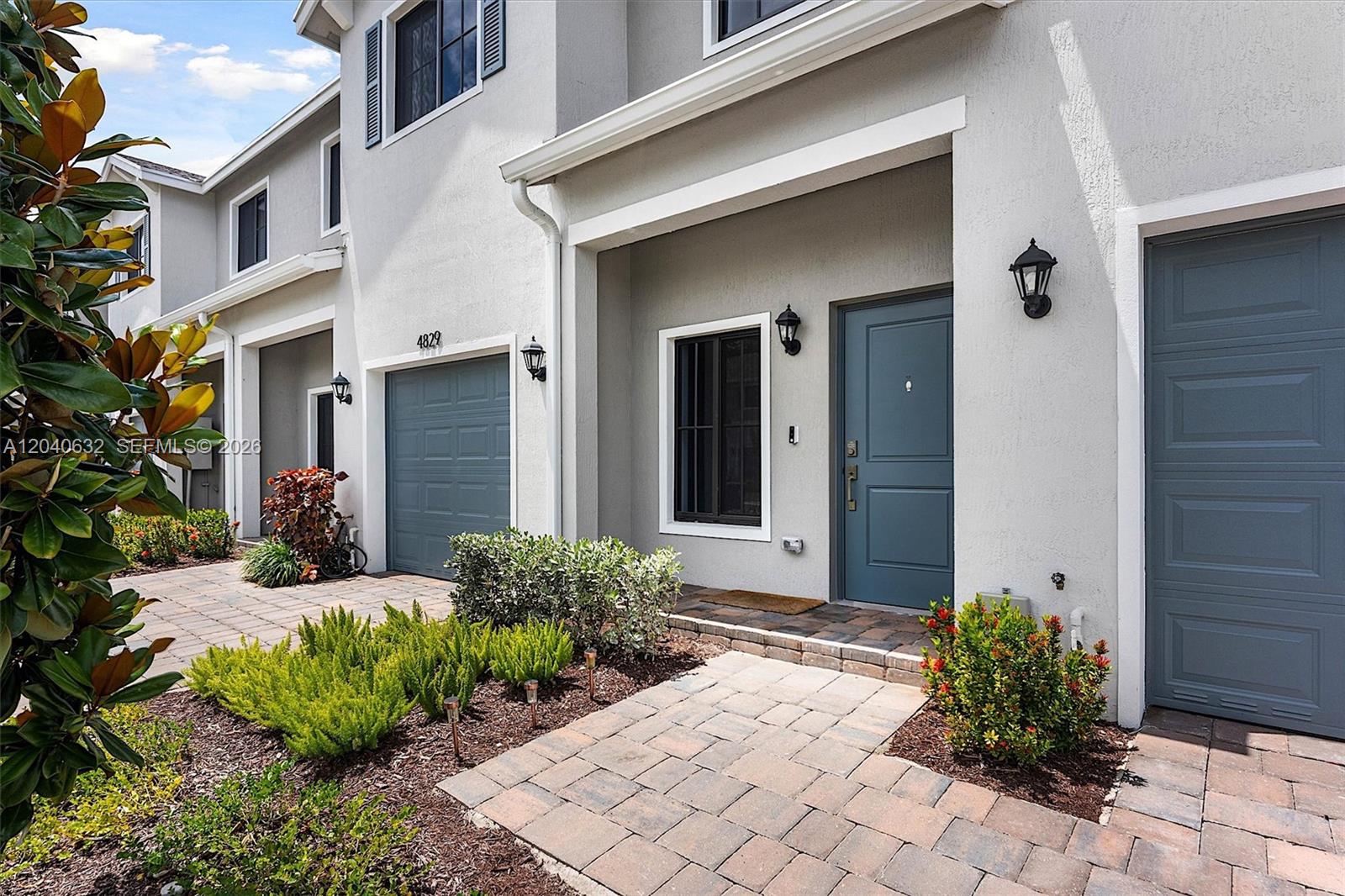 The exterior of a two-story townhouse features a blue front door and garage door — 4825 Dillion St, Lake Worth FL 33463, LAKE WORTH, FL