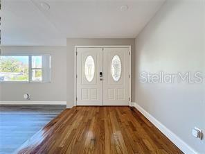 A room with hardwood floors, white walls, and double front doors with oval glass inserts — 1201 KAPOK KOVE CIRCLE, CLEARWATER, FL