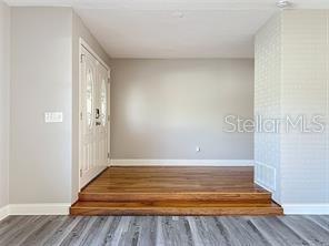 A room with a raised hardwood floor platform leading to a white front door — 1201 KAPOK KOVE CIRCLE, CLEARWATER, FL
