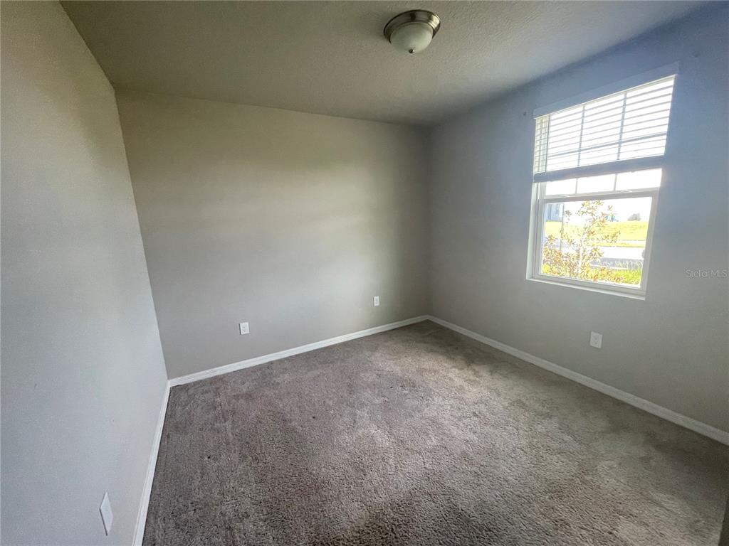 An empty bedroom features gray walls, gray carpeting, a ceiling light, and a single window — 3212 WEITZEL DRIVE, HAINES CITY, FL