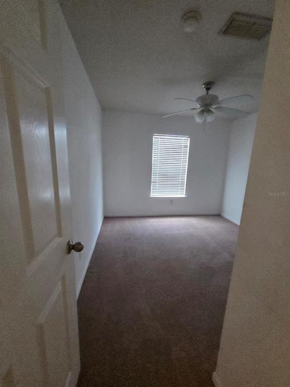 An empty bedroom features beige carpeting, white walls, a ceiling fan, and a single window — 9165 LEE VISTA BOULEVARD UNIT 107, ORLANDO, FL