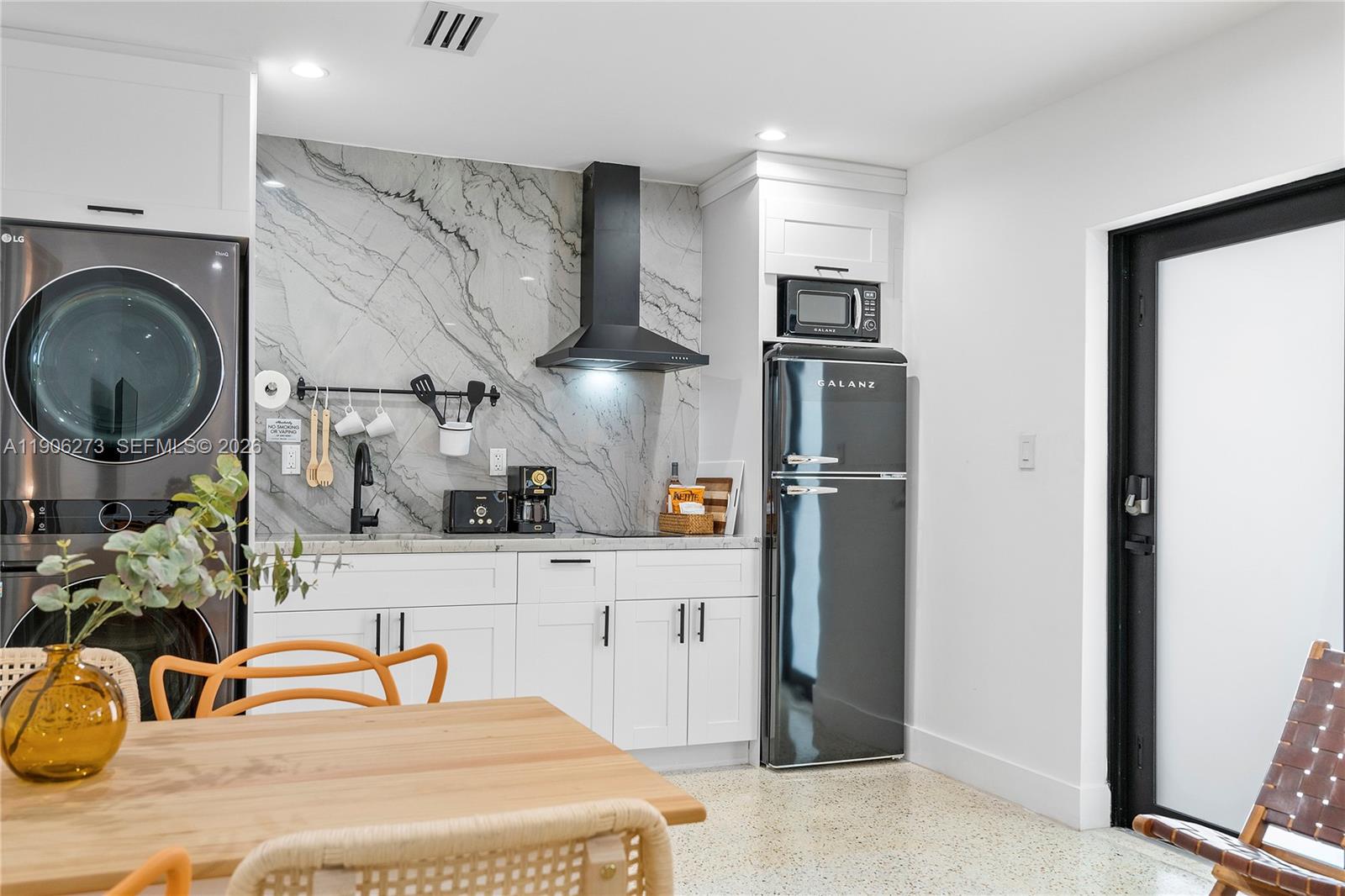 A kitchen area features white cabinets, a marble backsplash, black appliances, and a dining table — 256 NW 57th St, Miami FL 33127, MIAMI, FL