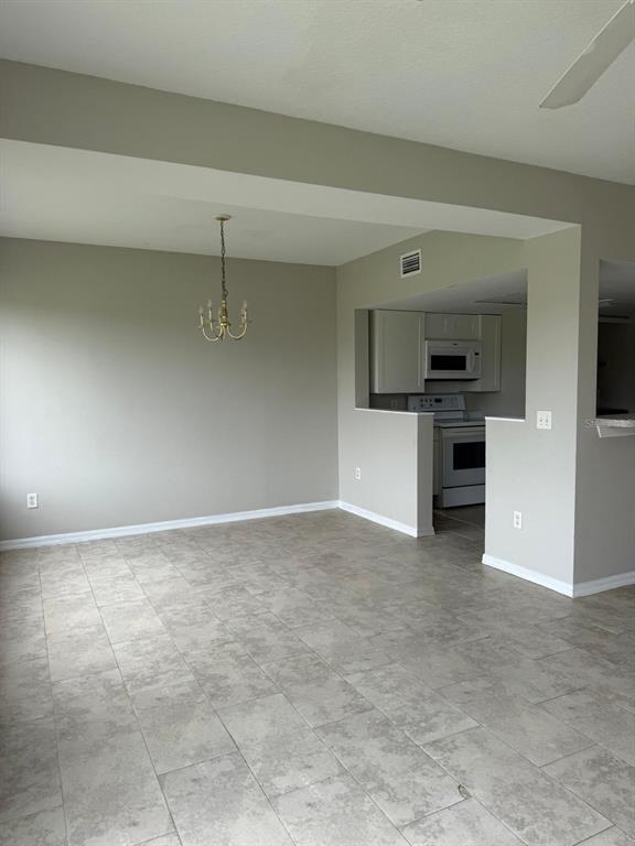 A dining area with tile flooring and a chandelier opens to a kitchen with appliances — 631 WASHINGTON PALM LOOP, DAVENPORT, FL