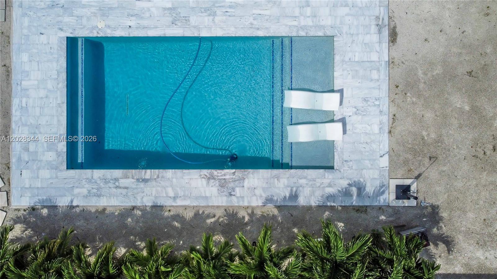 An aerial view shows a rectangular swimming pool with a tanning ledge and lounge chairs — 12100 SW 181st Ter, Miami FL 33177, MIAMI, FL