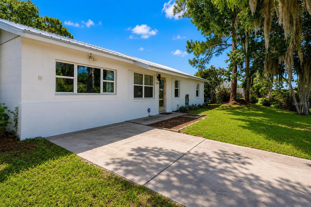 A white, single-story concrete block house with a metal roof and a concrete driveway — 2824 YULE TREE DRIVE, EDGEWATER, FL