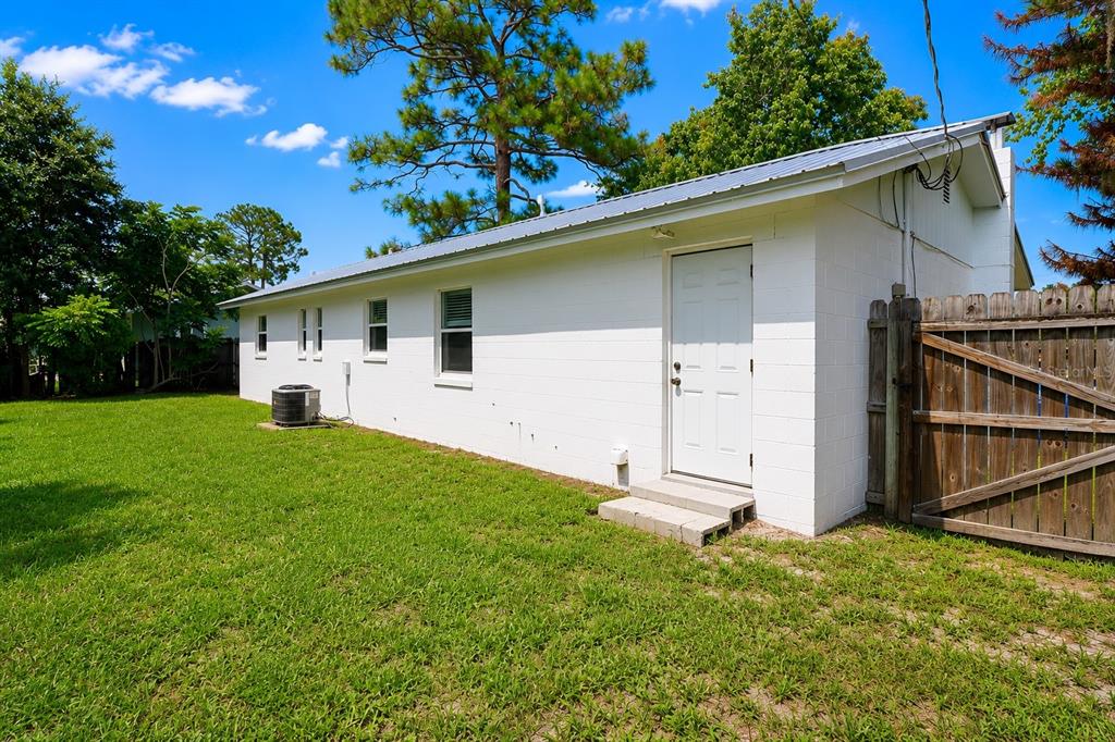 A white concrete block building with a metal roof and a wooden fence — 2824 YULE TREE DRIVE, EDGEWATER, FL