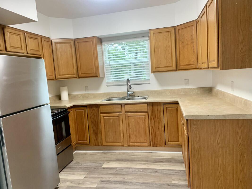A kitchen with wood cabinets, laminate countertops, stainless steel appliances, and wood-look flooring — 708 S Broadway, Lantana FL 33462, LANTANA, FL