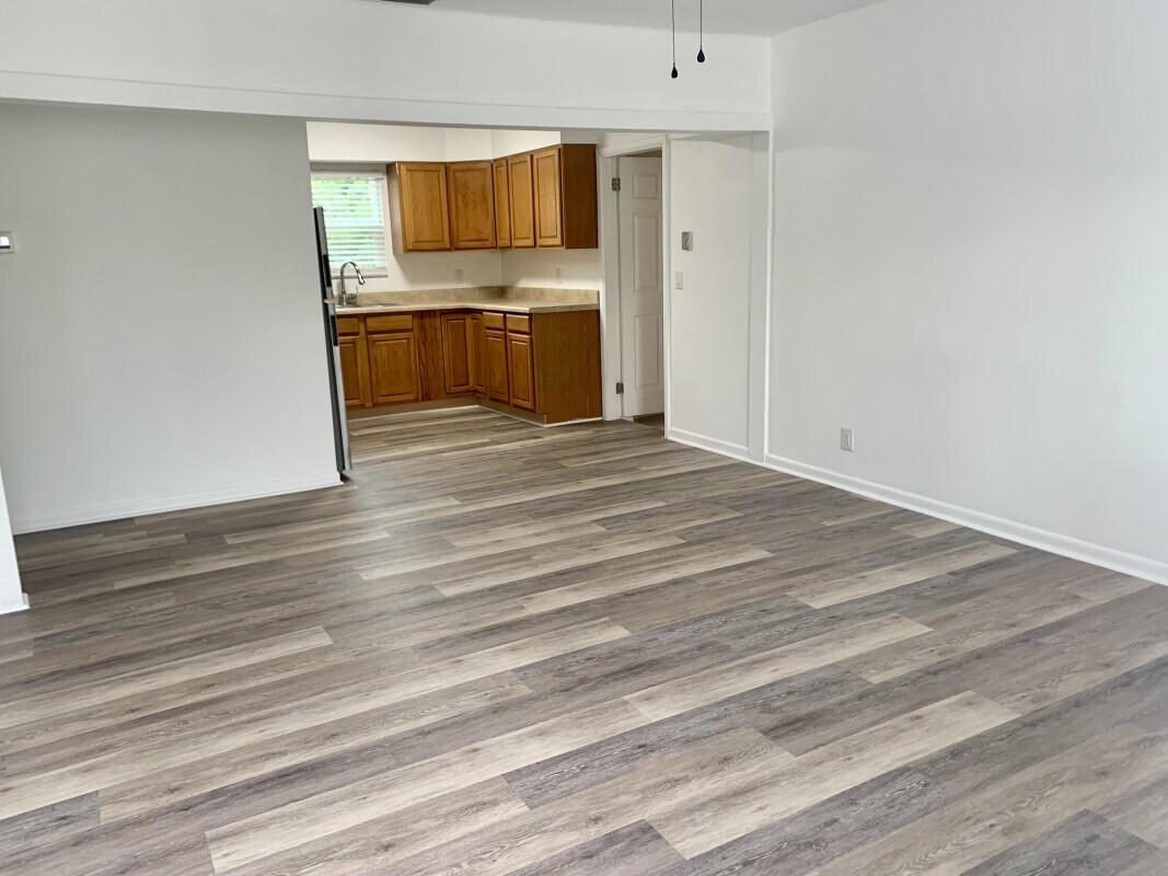 A living area with wood-look vinyl flooring opens into a kitchen with oak cabinets — 708 S Broadway, Lantana FL 33462, LANTANA, FL