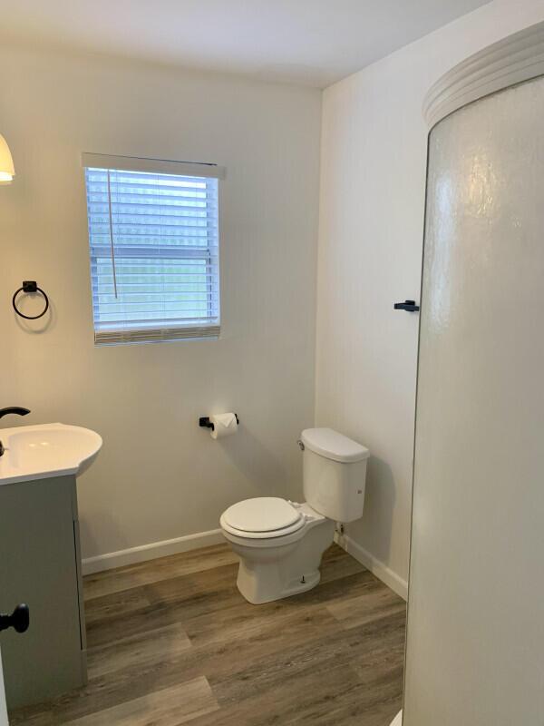 A bathroom features a white toilet, a vanity sink, and a corner shower stall — 708 S Broadway, Lantana FL 33462, LANTANA, FL