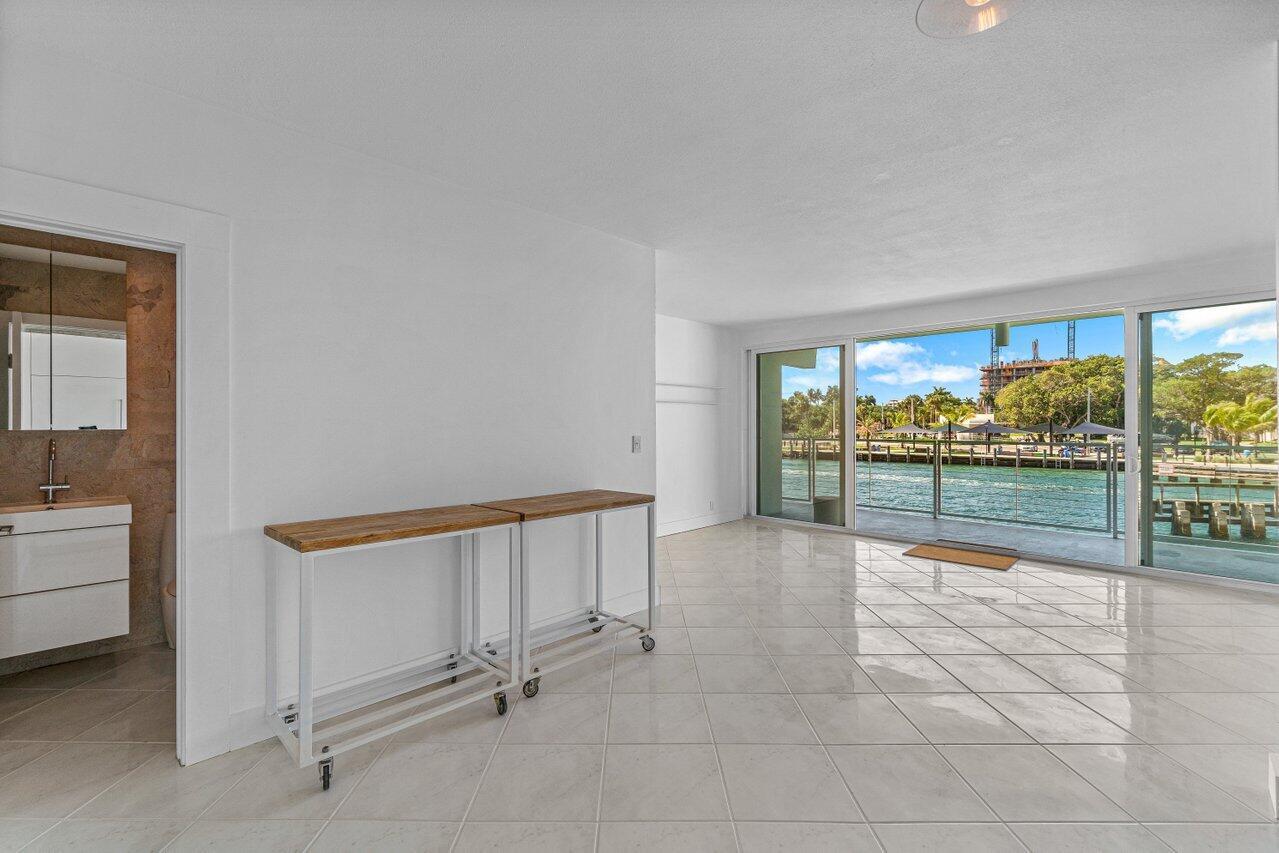 A bright room with white tile floors, a wooden console table, and sliding glass doors — 65 SE Spanish Trail # 2020, Boca Raton FL 33432, BOCA RATON, FL