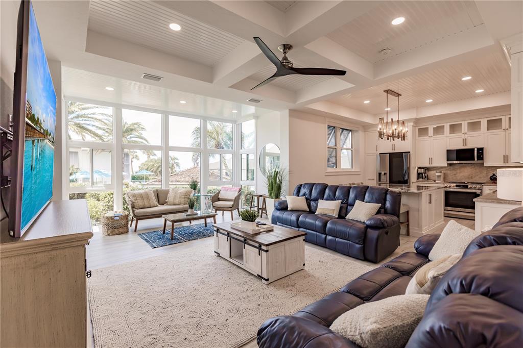 A bright open-concept living room and kitchen featuring a tray ceiling and large windows — 6042 W PEPPERTREE WAY UNIT 224B, SARASOTA, FL