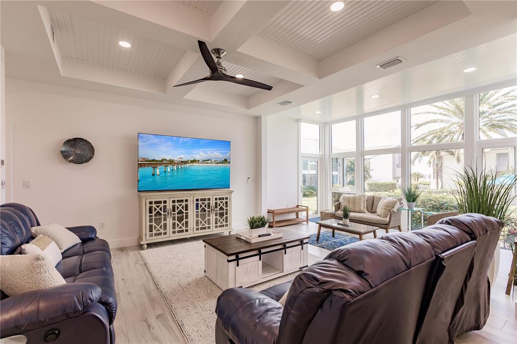 A living room features a tray ceiling, dark leather sofas, and a wall of windows — 6042 W PEPPERTREE WAY UNIT 224B, SARASOTA, FL