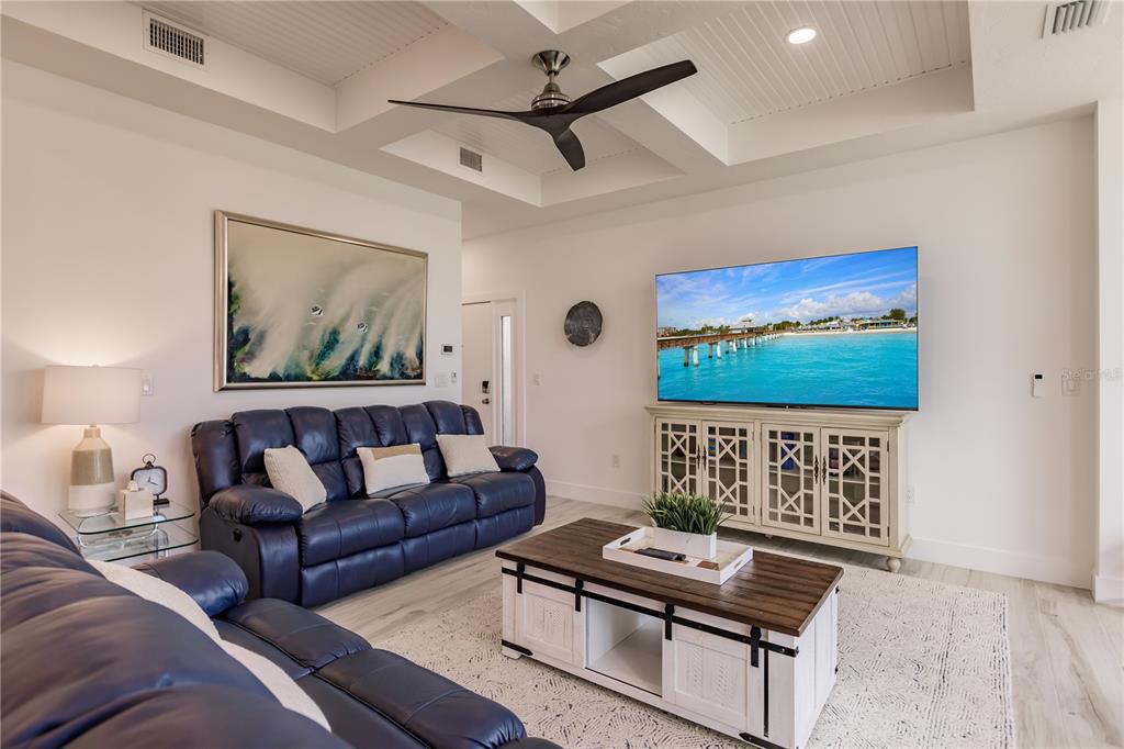 A living room features a blue leather sofa, a coffee table, and a wall-mounted television — 6042 W PEPPERTREE WAY UNIT 224B, SARASOTA, FL
