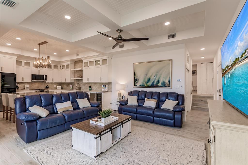 A living room with two blue leather sofas, a coffee table, and an open kitchen — 6042 W PEPPERTREE WAY UNIT 224B, SARASOTA, FL