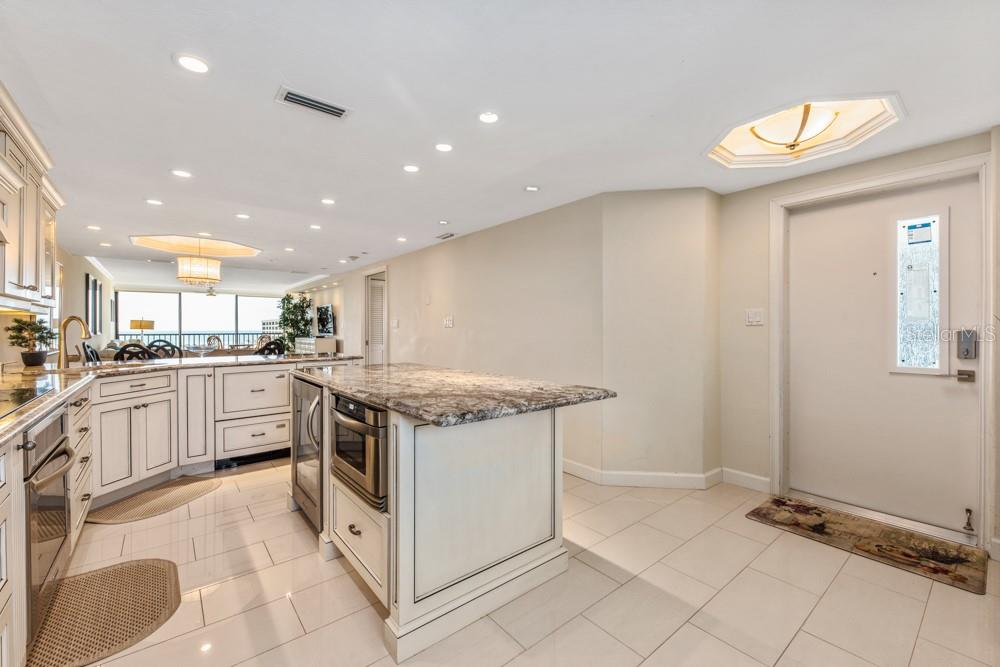 A kitchen with white cabinetry, granite countertops, and tile flooring near an entryway door — 5770 MIDNIGHT PASS ROAD UNIT 605, SARASOTA, FL