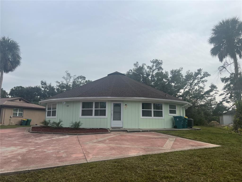 A round, light green house with a dark shingled roof and a concrete driveway — 15539 CHAMBERLAIN BOULEVARD, PORT CHARLOTTE, FL