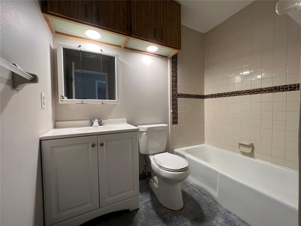A bathroom features a white vanity, a toilet, and a tiled bathtub shower combination — 15539 CHAMBERLAIN BOULEVARD, PORT CHARLOTTE, FL