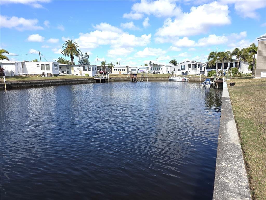A canal view shows several mobile homes along the water with small private docks — 504 CLARION PLACE, NORTH PORT, FL