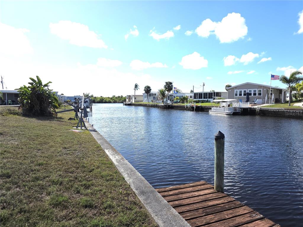 A canal view from a wooden dock with mobile homes lining the waterfront — 504 CLARION PLACE, NORTH PORT, FL