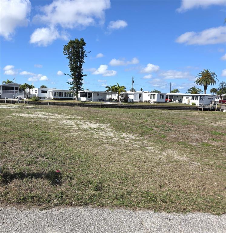 A vacant, grassy lot sits in front of a row of mobile homes — 504 CLARION PLACE, NORTH PORT, FL