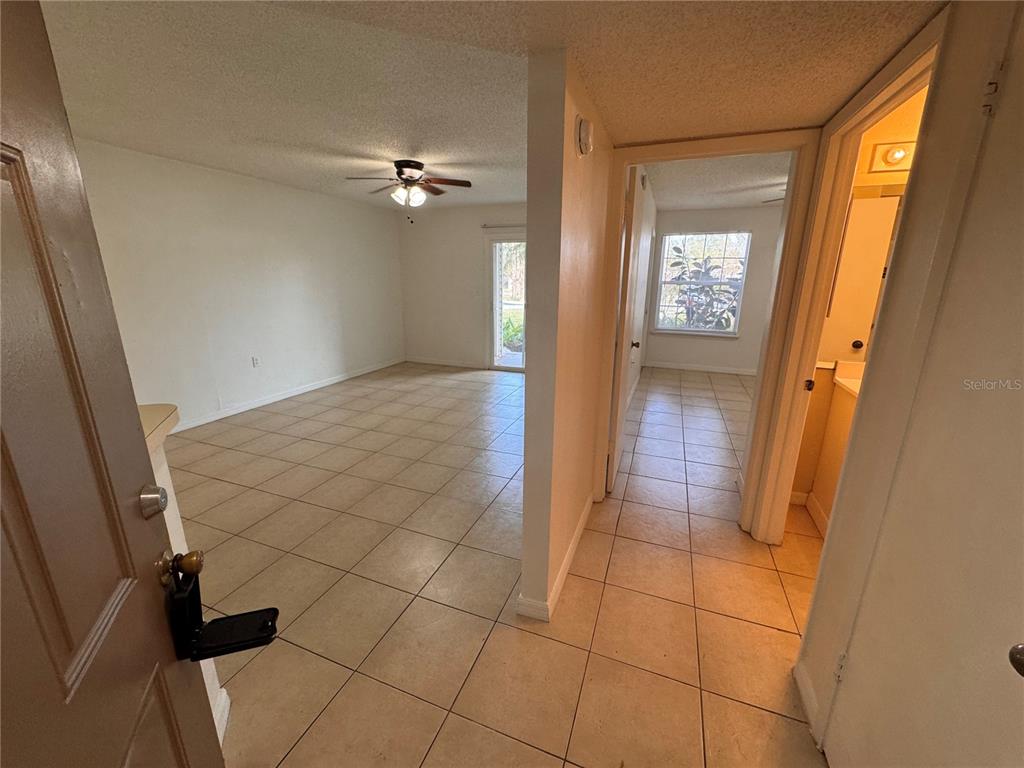 An entryway leads to a tiled living area with a ceiling fan and sliding doors — 1916 LAKE ATRIUMS CIRCLE UNIT 40, ORLANDO, FL