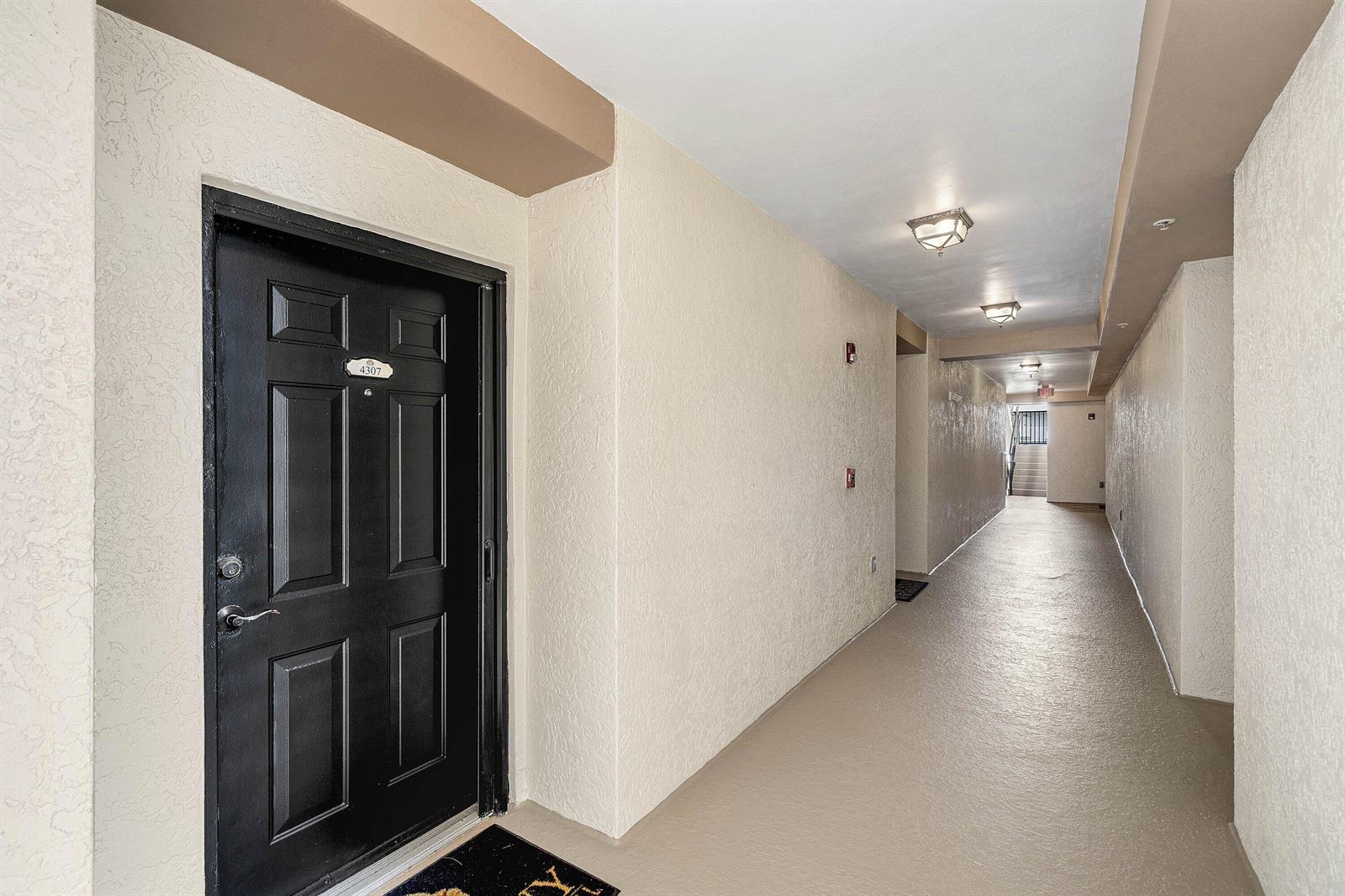 A black apartment door with the number 4307 sits at the end of a hallway — 4307 Tuscany Way, Boynton Beach FL 33435, BOYNTON BEACH, FL
