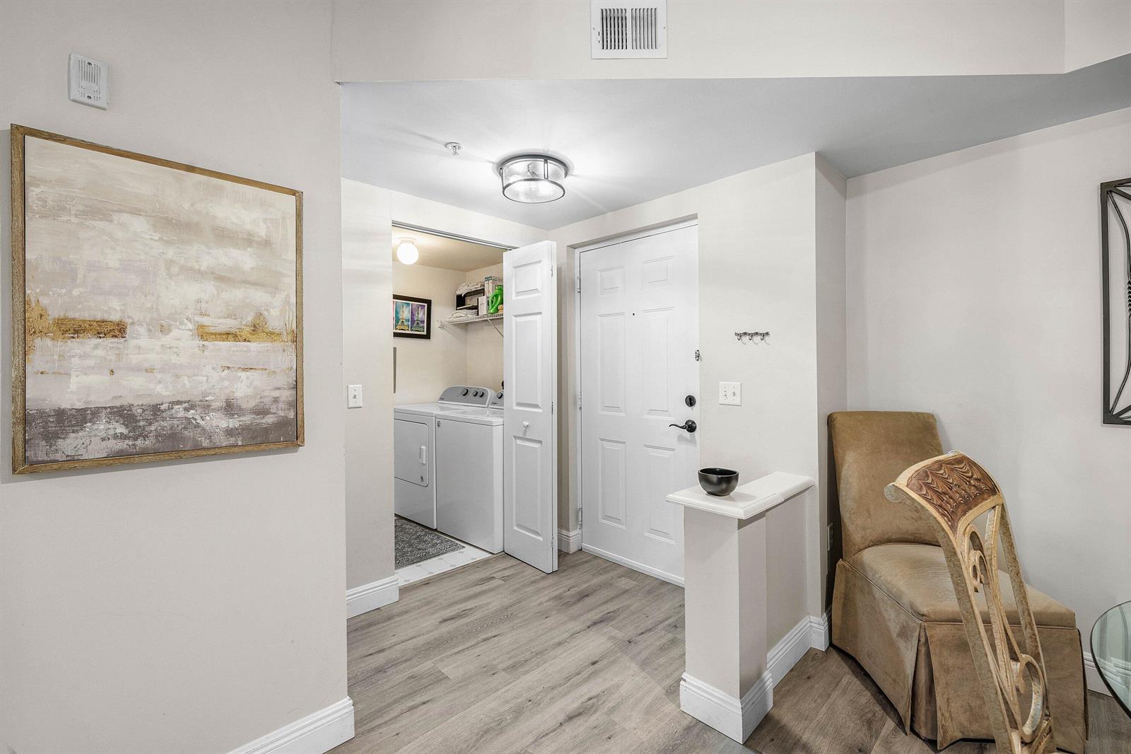 An entryway features light wood-look flooring, a white front door, and an adjacent laundry closet — 4307 Tuscany Way, Boynton Beach FL 33435, BOYNTON BEACH, FL