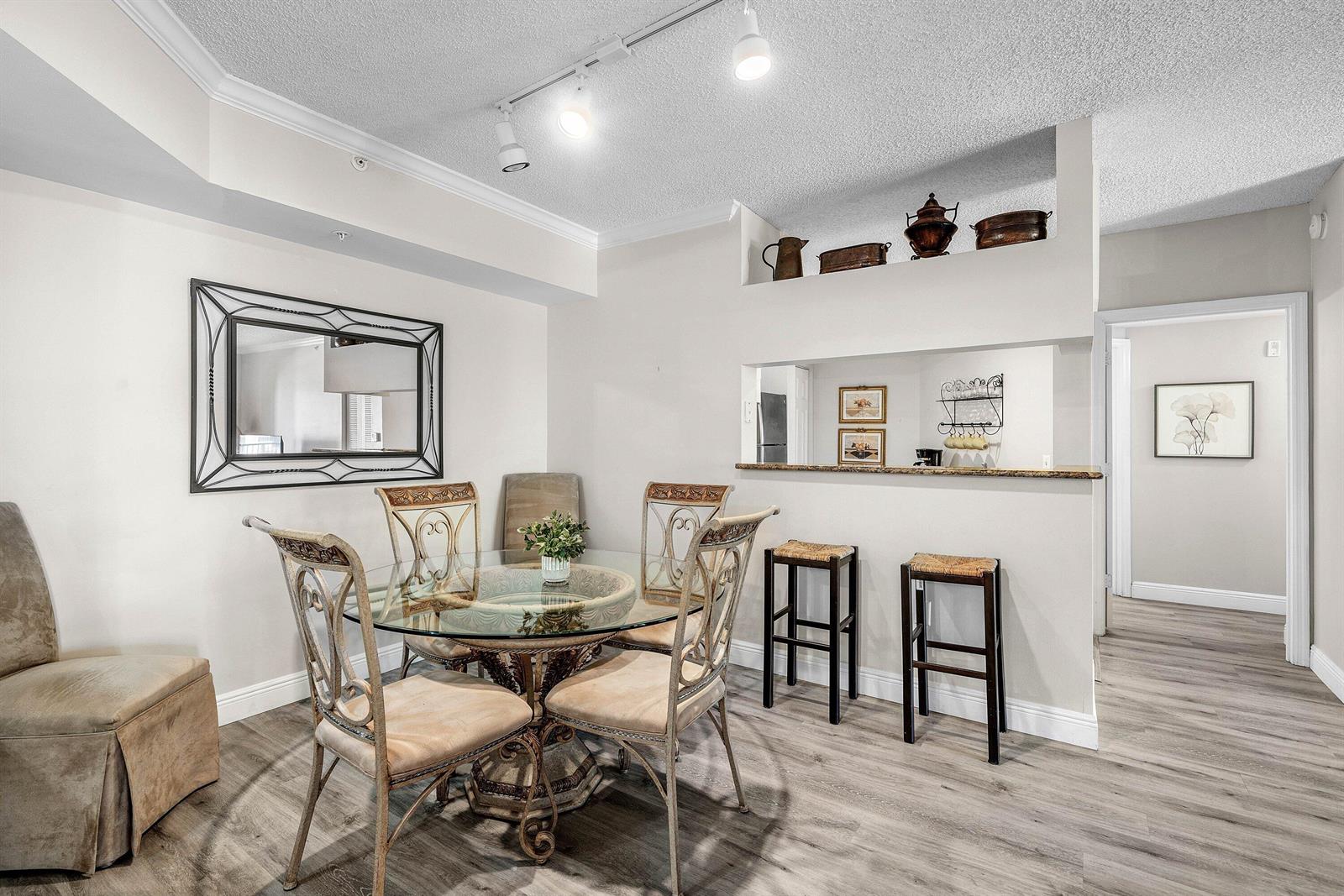 A dining room features a glass-topped table, metal chairs, and a breakfast bar with stools — 4307 Tuscany Way, Boynton Beach FL 33435, BOYNTON BEACH, FL