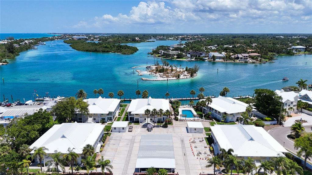 An aerial view shows white multi-story buildings with metal roofs near a blue waterway — 999 INLET CIRCLE UNIT B104, VENICE, FL