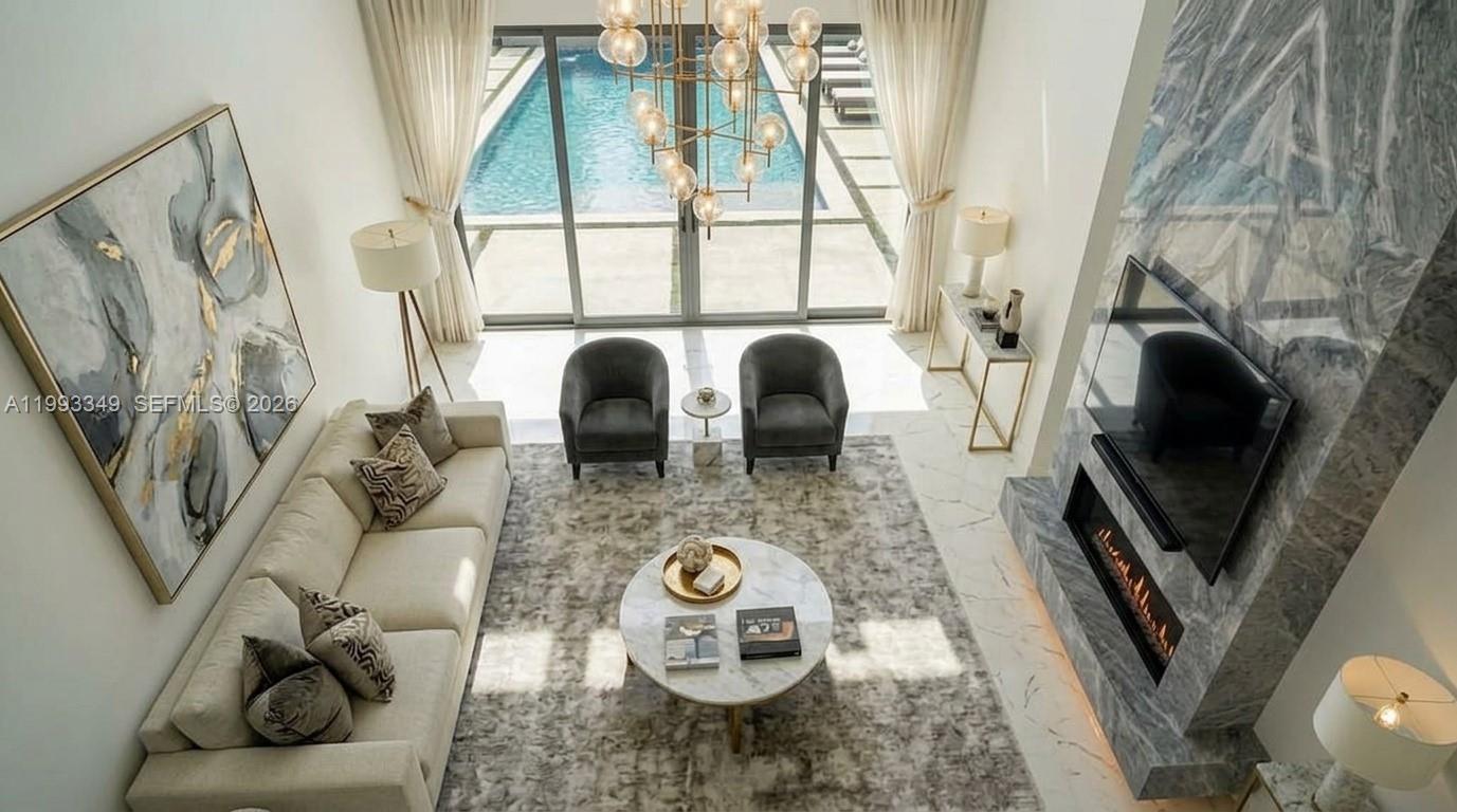 A high-ceiling living room features a marble fireplace, a pool view, and modern furniture — 680 NW 33rd St, Oakland Park FL 33309, OAKLAND PARK, FL